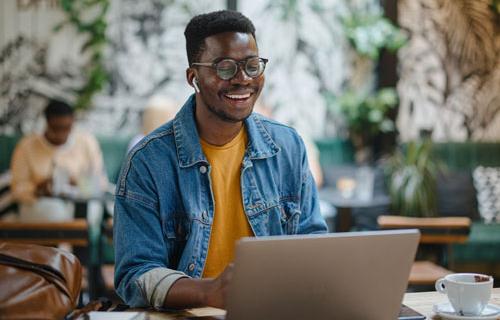 A college age man uses his laptop in a coffee shop