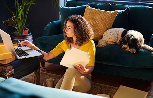 A woman uses her laptop while her dog sleeps next to her